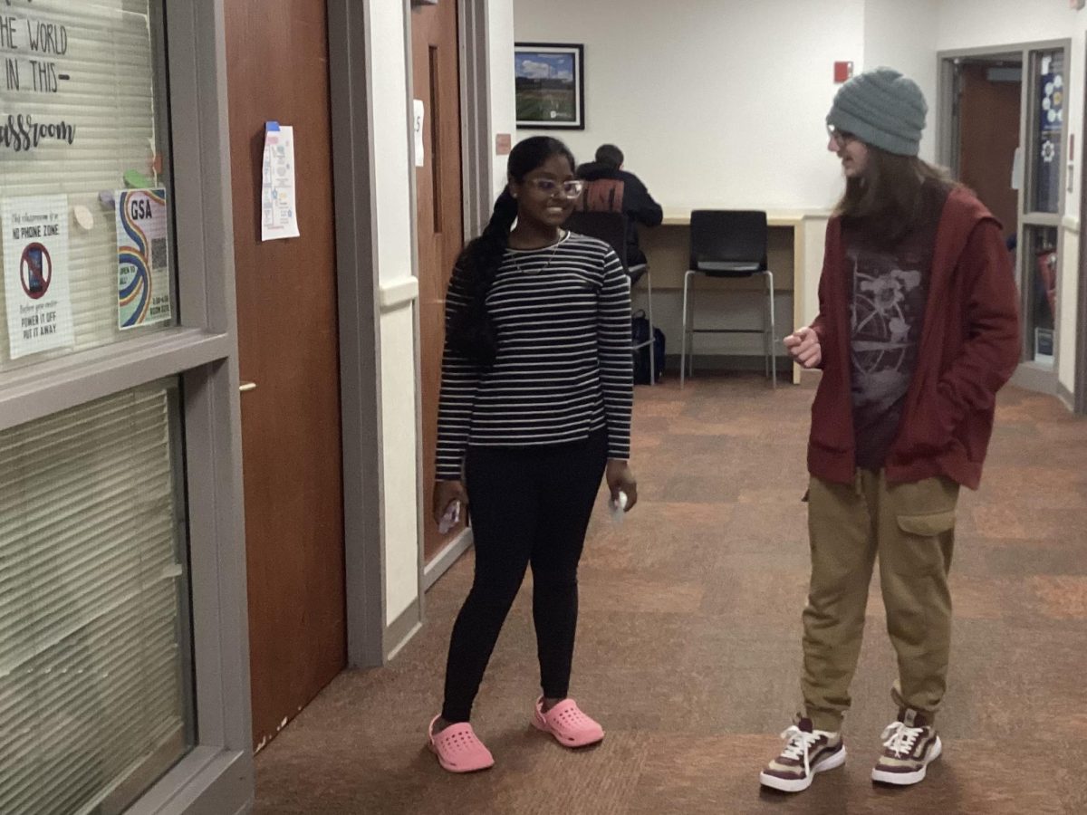 Freshmen Ananya Saloj and Bryson Blazier converse as they walk down a hall.